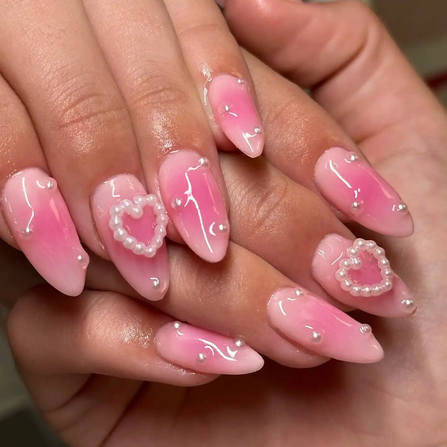 Handmade pink press-on nails with glossy finish, pearl heart and bead accents, romantic design.