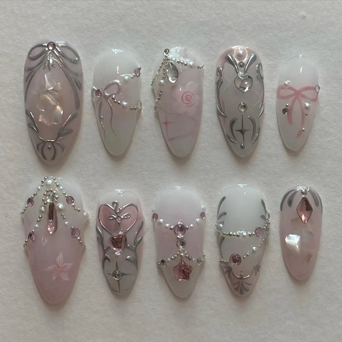 Handmade pink and silver press-on nails with rhinestones, pearls, and elegant princess design