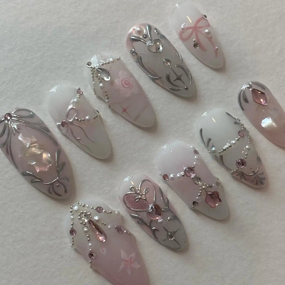 Handmade pink and silver press-on nails with rhinestones, pearls, and elegant princess design