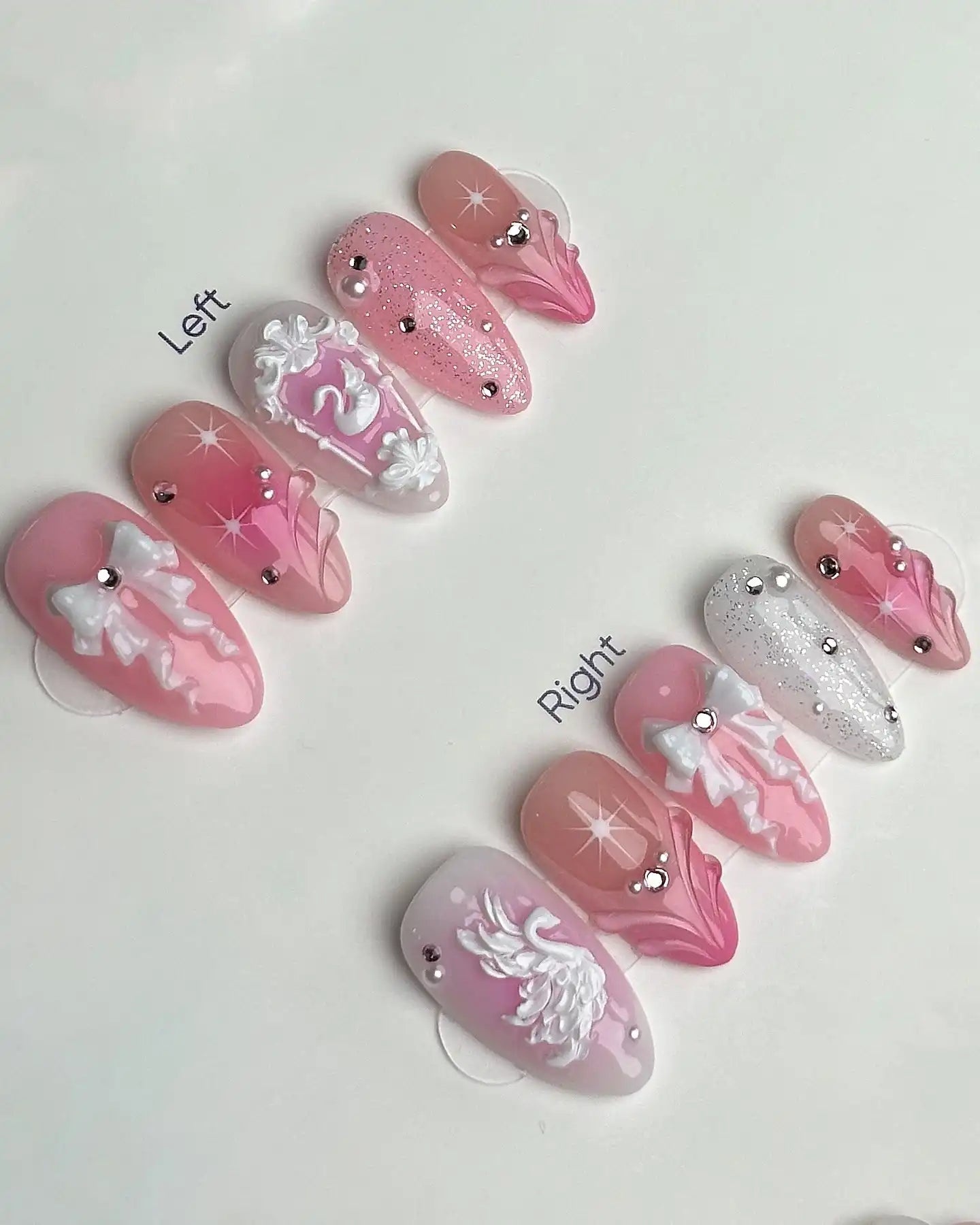 Handmade pink and white press-on nails with swan, bows, glitter, jewels, and 3D detailing.