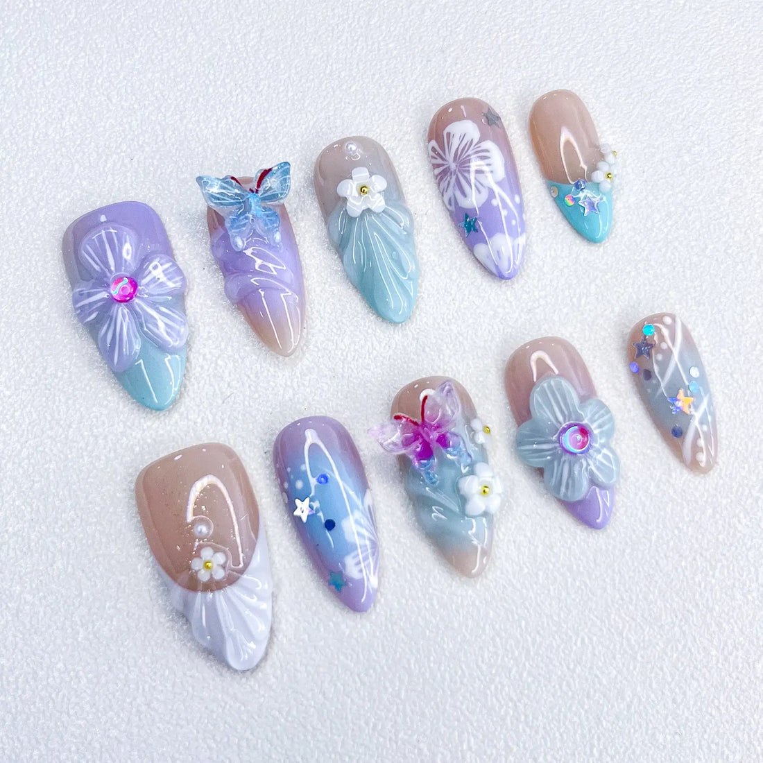 Handmade pastel press-on nails with purple butterfly, floral accents, and sparkle details