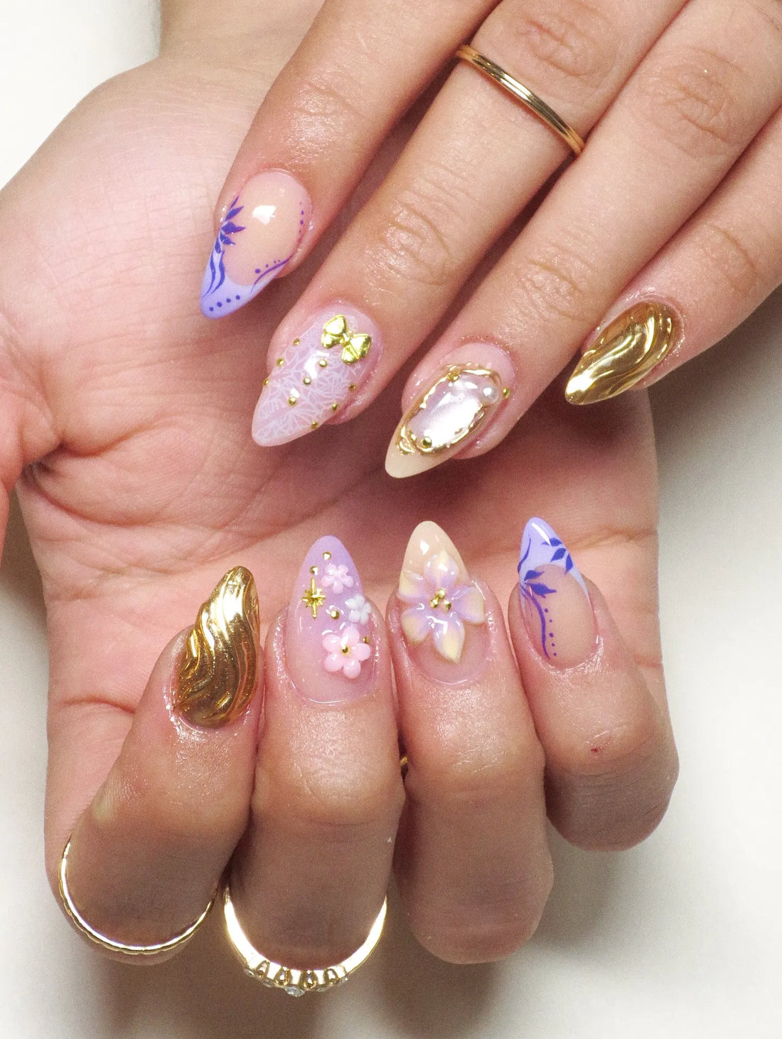 Handmade press-on nails with purple floral design, gold chrome accents, 3D flowers, and pearl details.