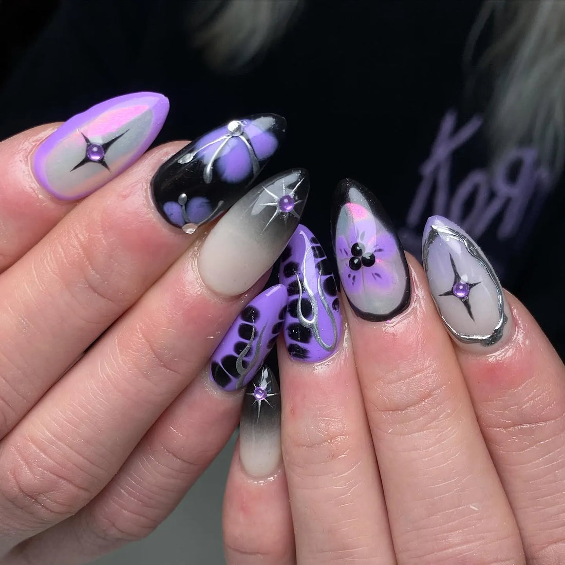 Handmade purple ombre floral press-on nails with chrome star accents and rhinestones.
