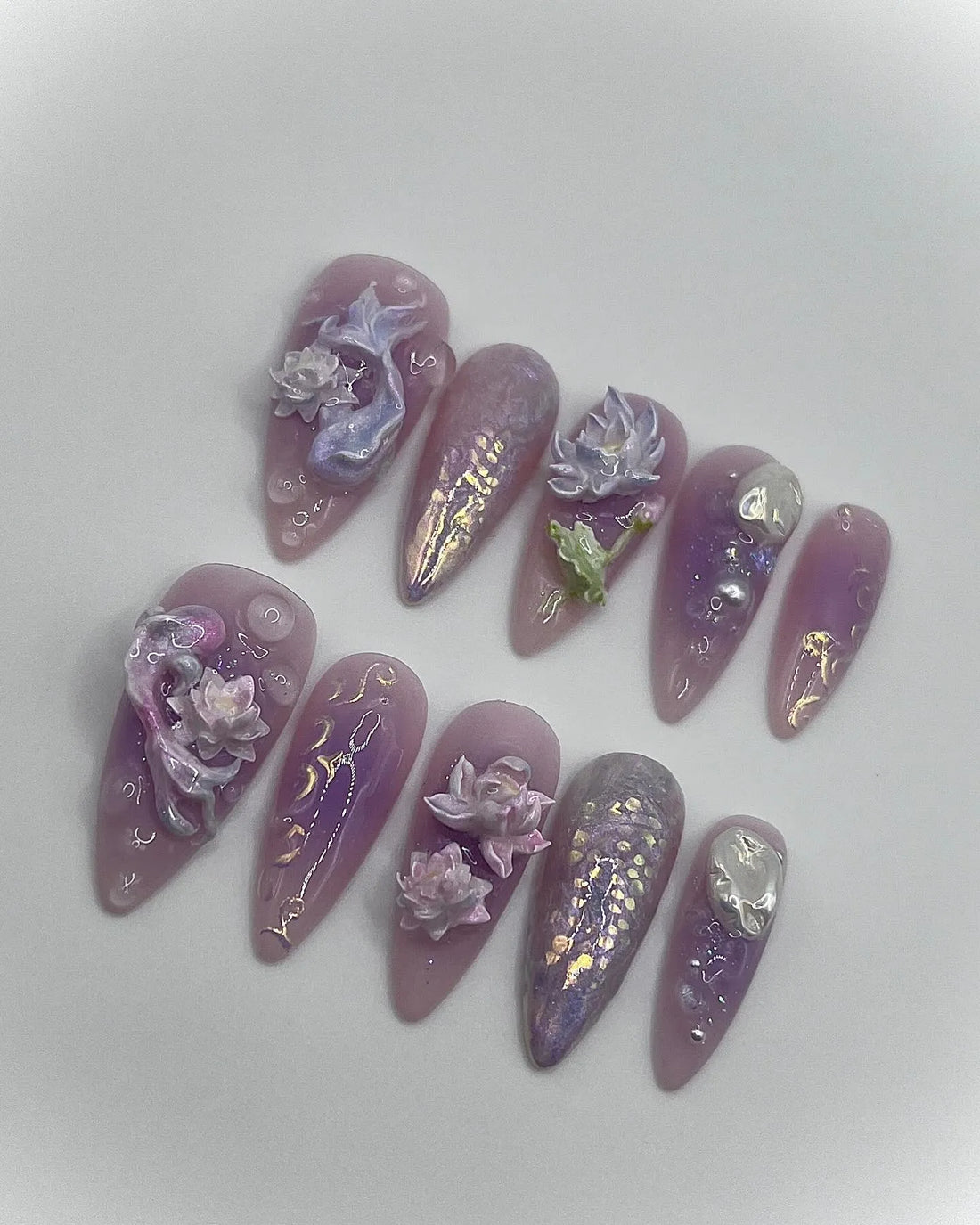 Handmade iridescent purple press-on nails with 3D lotus flowers, mermaid and fantasy designs.