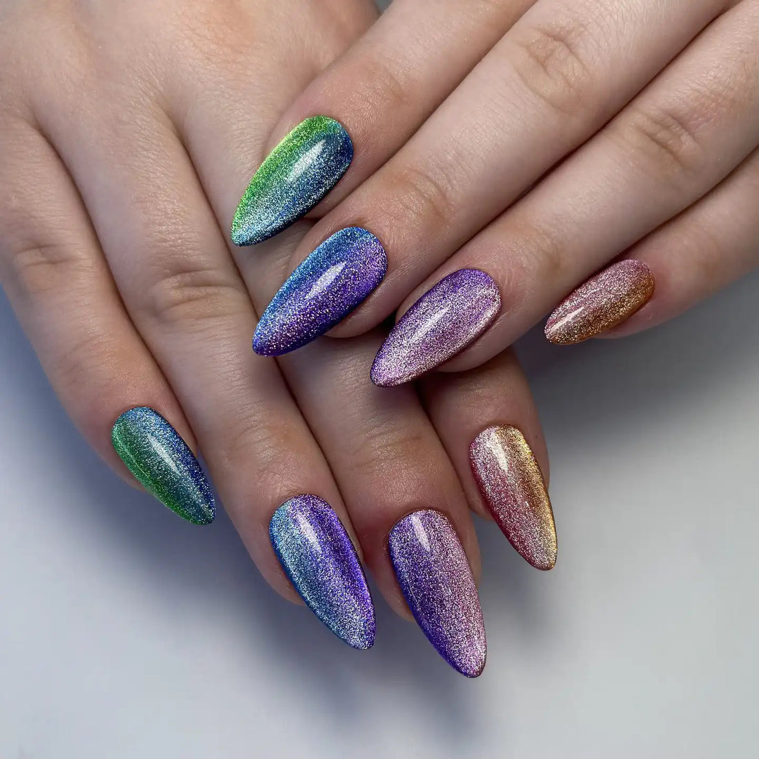 Hand with almond-shaped, multicolor rainbow shimmer press-on nails, velvet cat eye effect