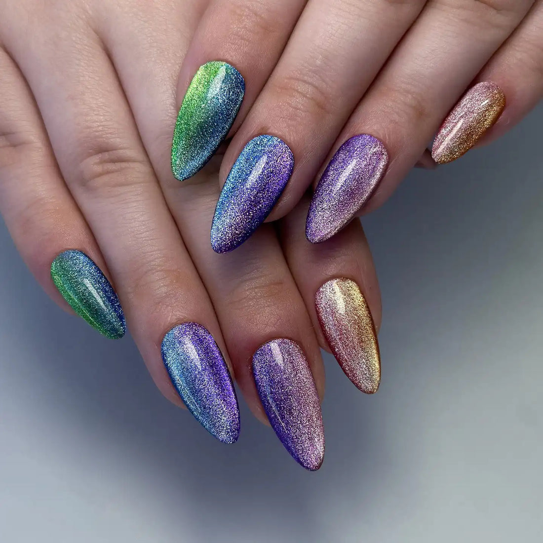 Hand with almond-shaped, multicolor rainbow shimmer press-on nails, velvet cat eye effect
