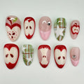 Handmade press-on nails with red apple, plaid green, and star designs, arranged on white background.