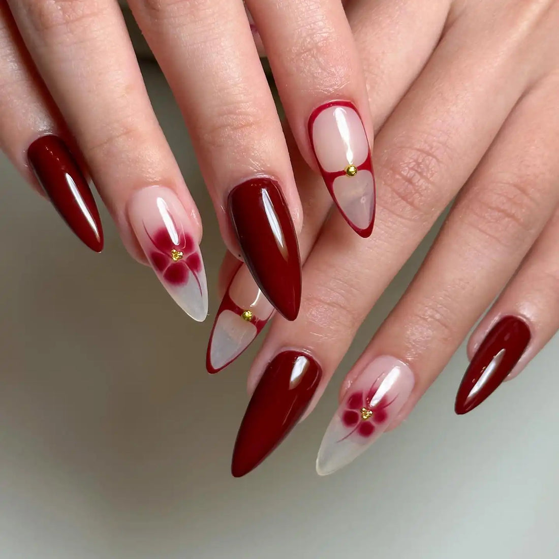 Hand with handmade red blossom and snakeskin design press-on nails, stiletto-shaped