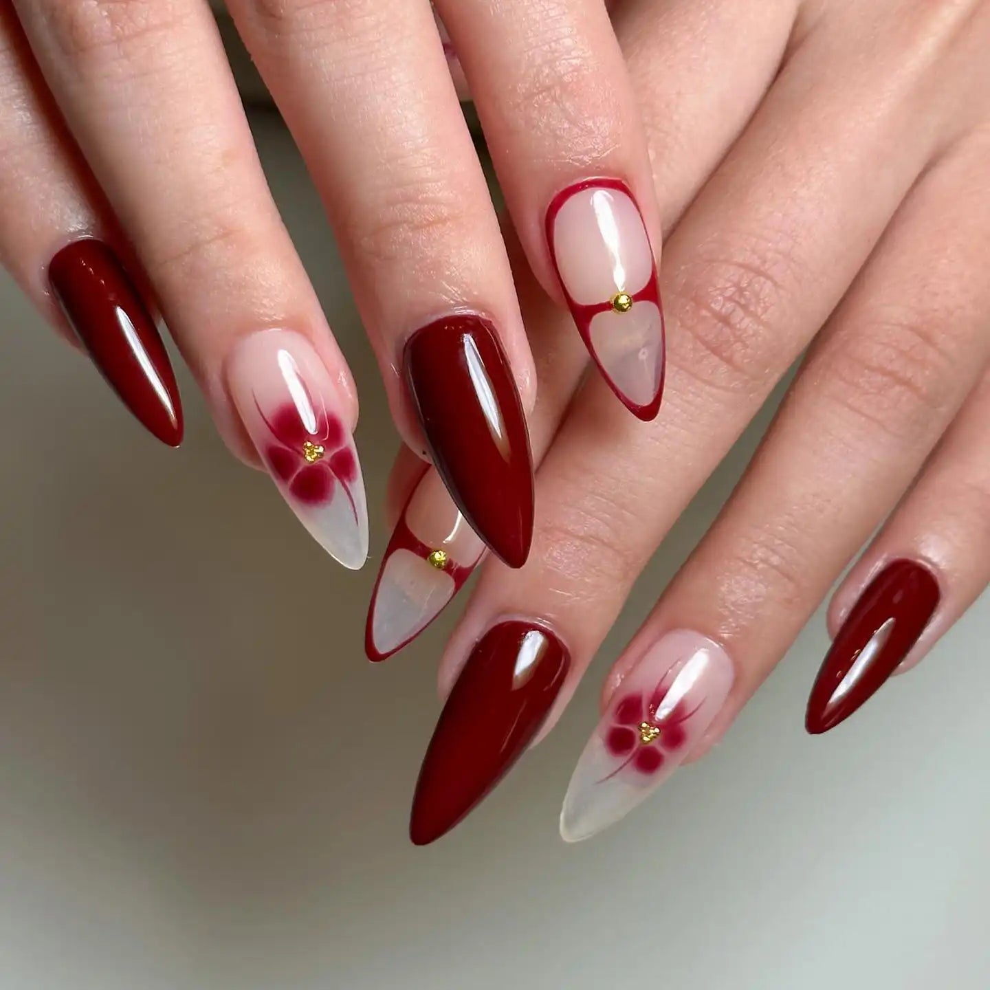 Hand with handmade red blossom and snakeskin design press-on nails, stiletto-shaped