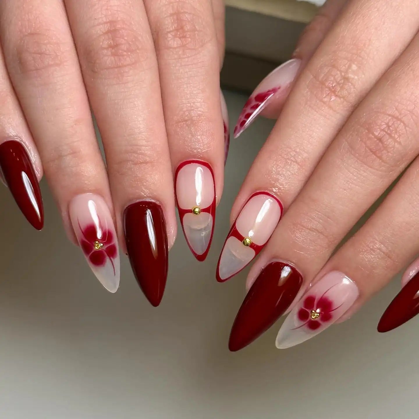 Handmade press-on nails with red blossom flower design, red tips, and snake skin accents.