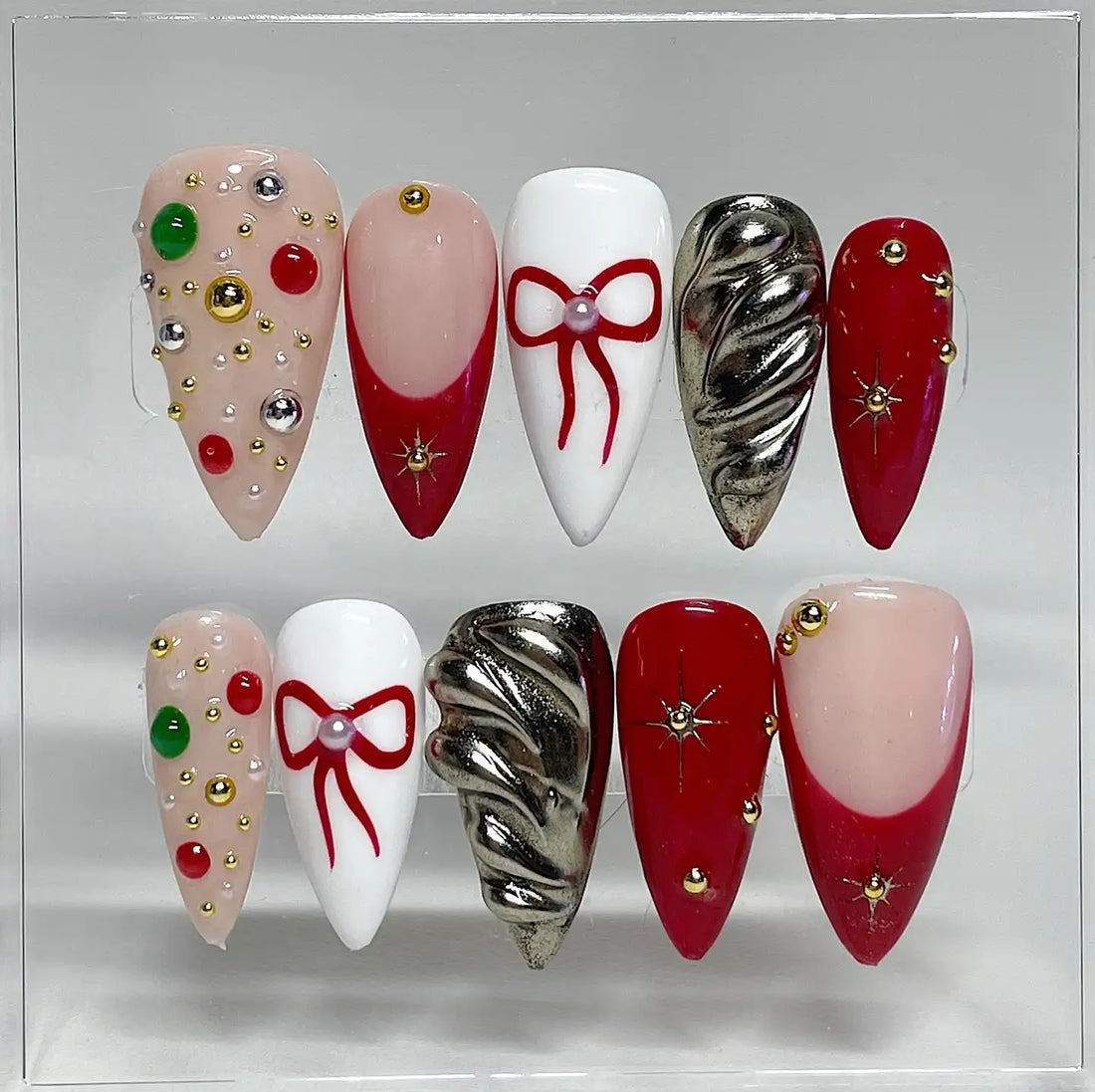 Handmade Christmas press-on nails with red bows, chrome stars, and festive decorations.
