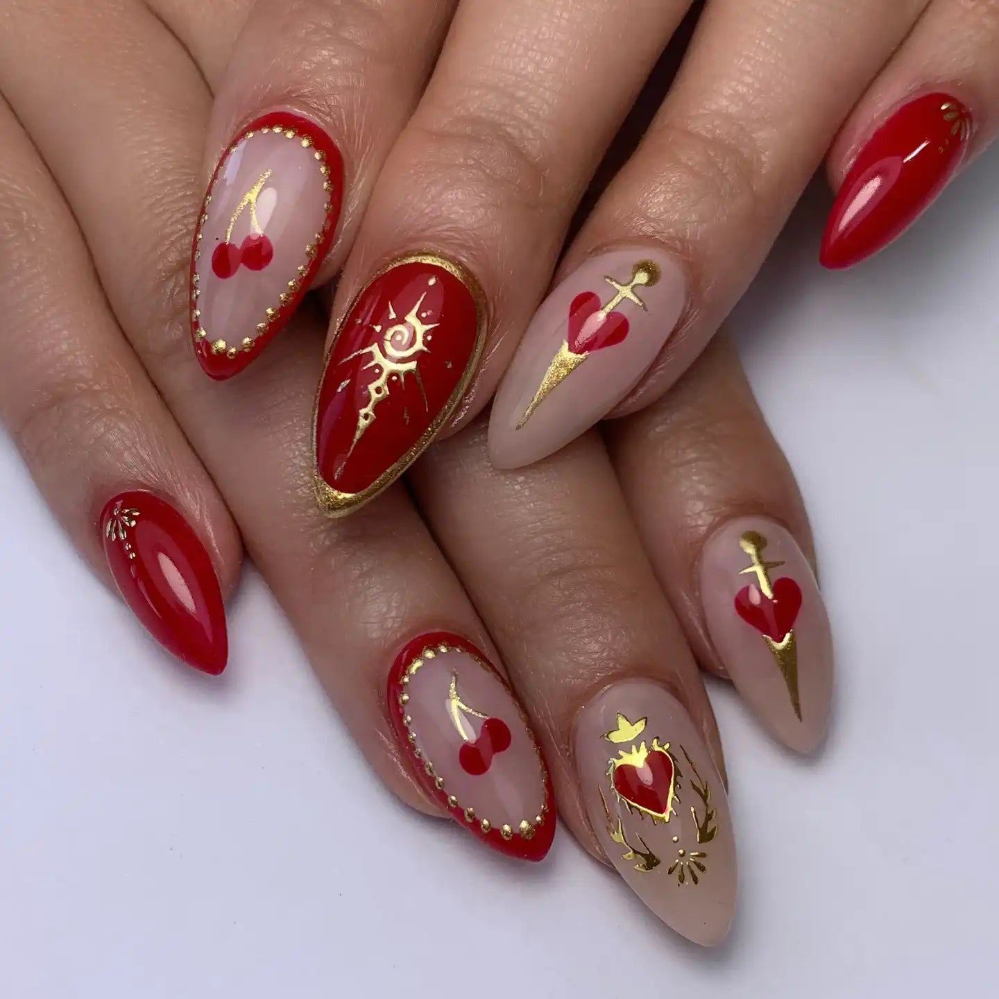 Handmade press-on nails with red cherry, heart, sword, and gold gothic designs