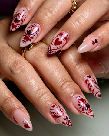 Handmade press-on nails with red and pink heart and floral designs on nude base