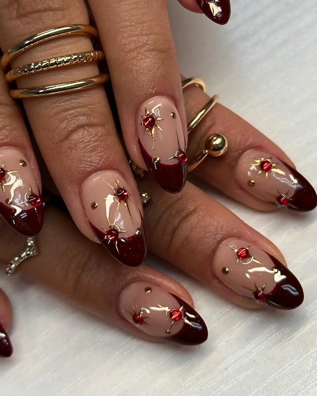 Handmade wine tip press-on nails with red gem and gold star designs on almond shape