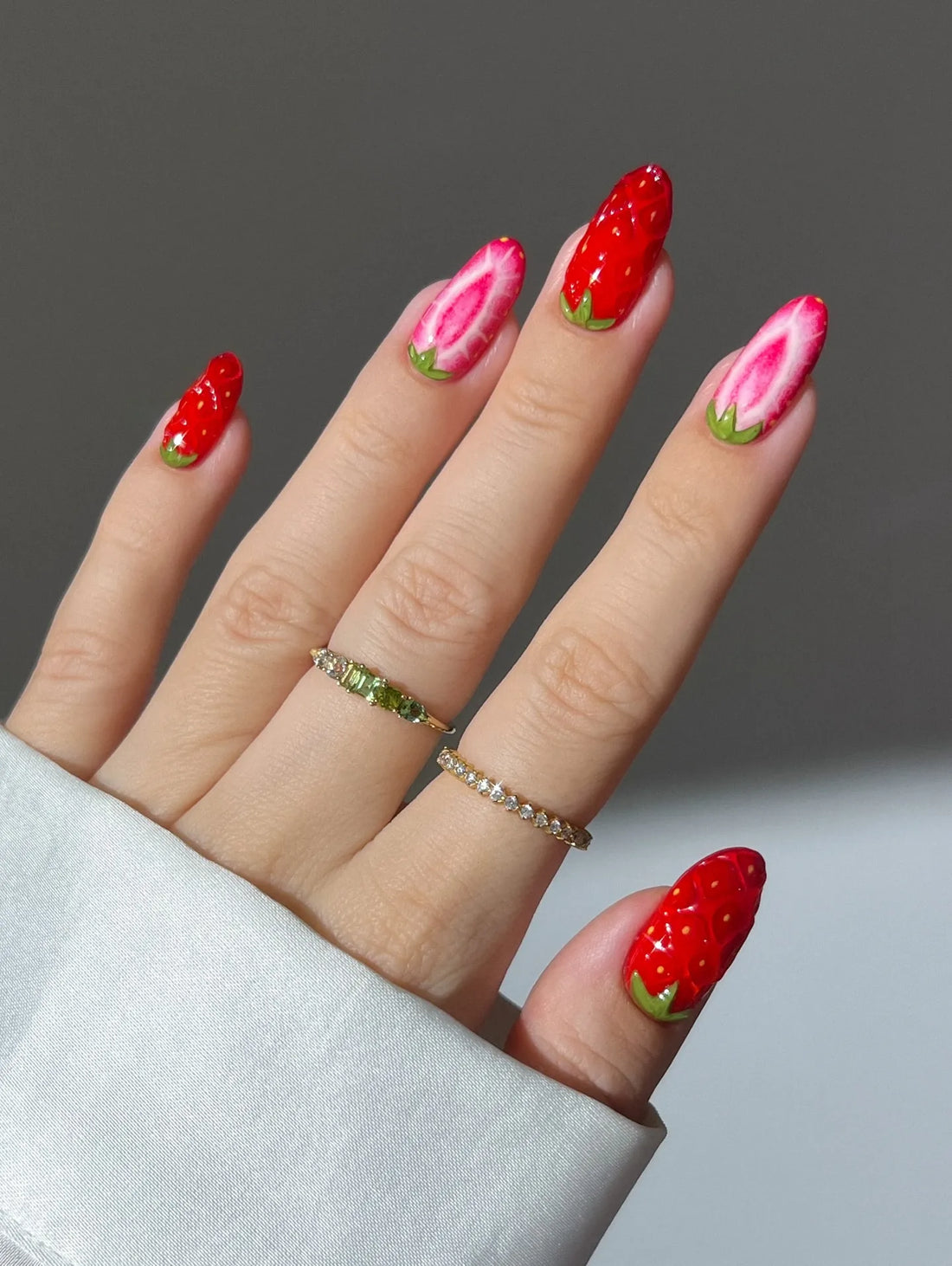 Hand with handmade red and pink strawberry fruit design cute summer press-on nails.