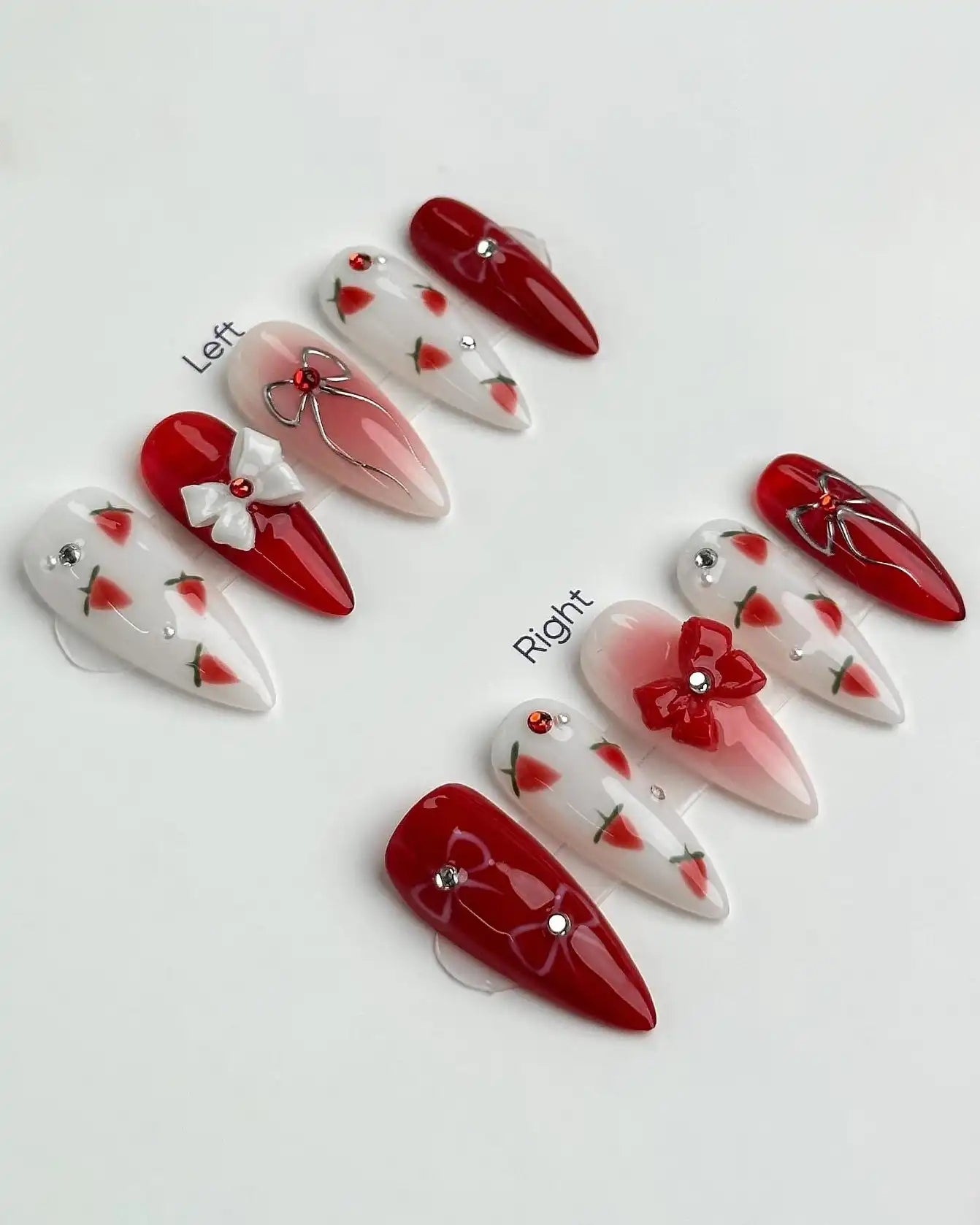 Handmade press-on nails with red and white strawberry designs, bows, and small jewel accents.