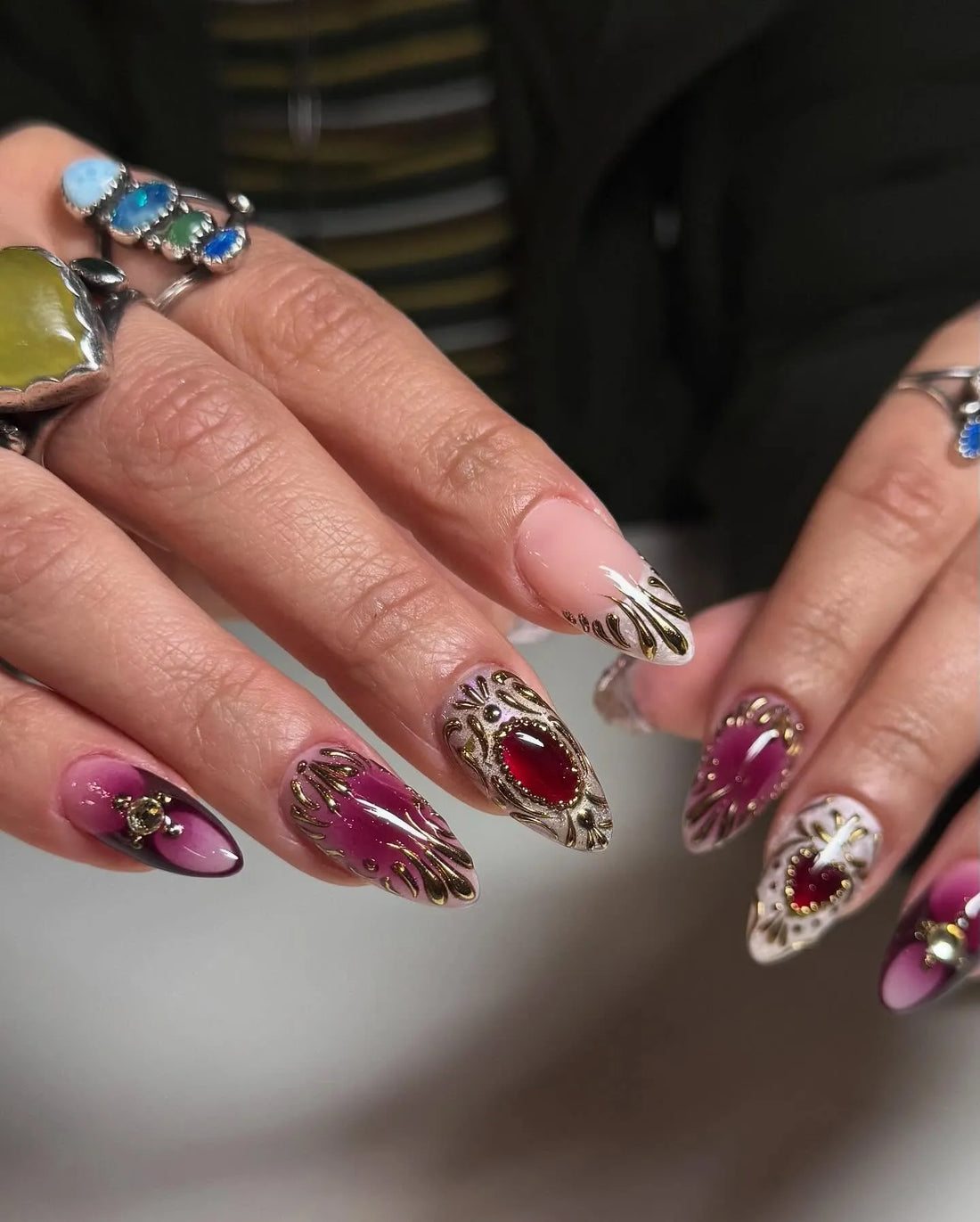 Handmade press-on stiletto nails with ruby red gemstones, gold filigree, and ombre design.
