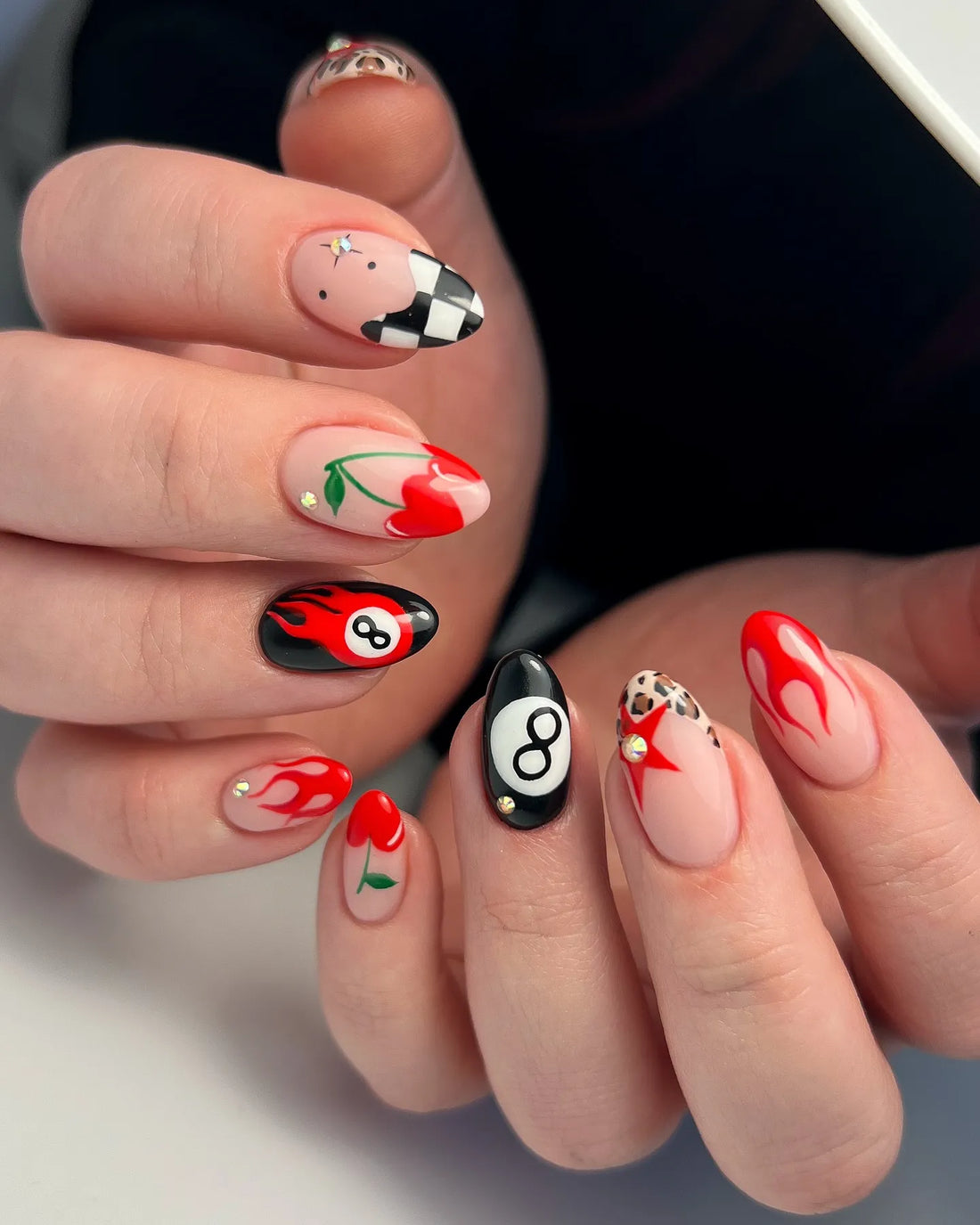 Handmade press-on nails with red flames, cherries, black eight ball, leopard, and checker patterns.