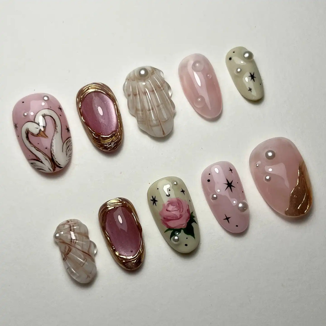 Handmade press-on nails with swan, pink rose, pearl, and gem accents on pastel backgrounds