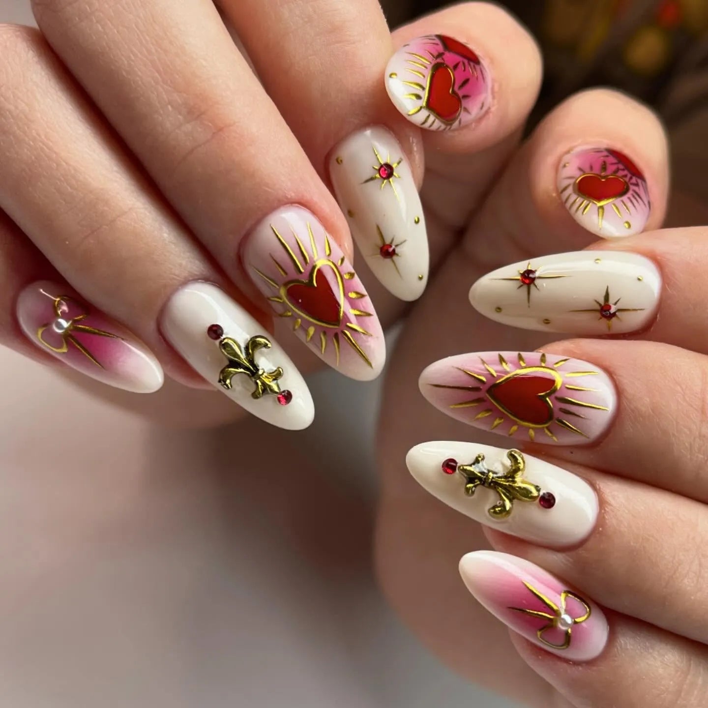 Handmade press-on nails with gold fleur-de-lis, red sacred hearts, and pink accents