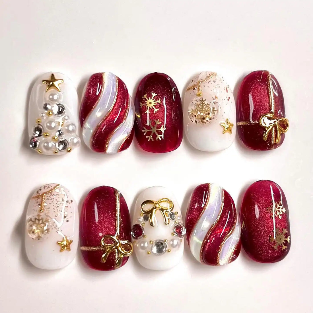 Handmade Christmas press-on nails with ruby glitter, gold bows, snowflakes, and festive designs.