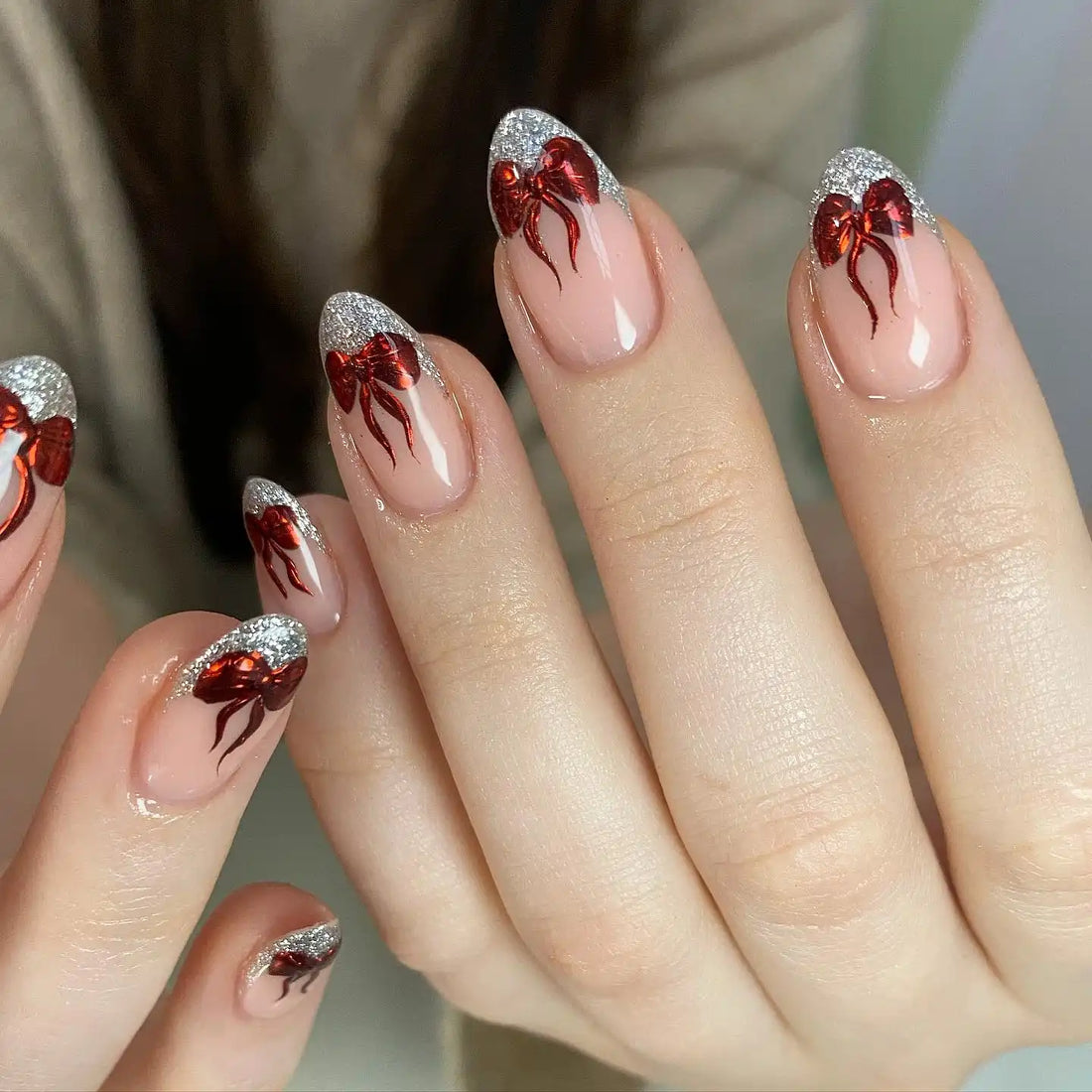 Handmade nude press-on nails with silver glitter tips and red Christmas bow designs