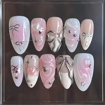 Handmade pink and white press-on nails with silver ribbon, bows, and gemstone accents