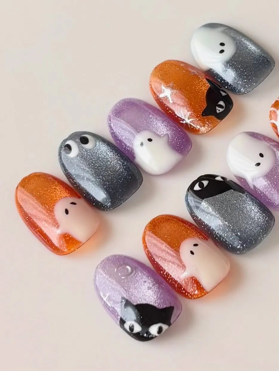 Handmade press-on nails with glittery Halloween ghost, black cat, and spider web designs