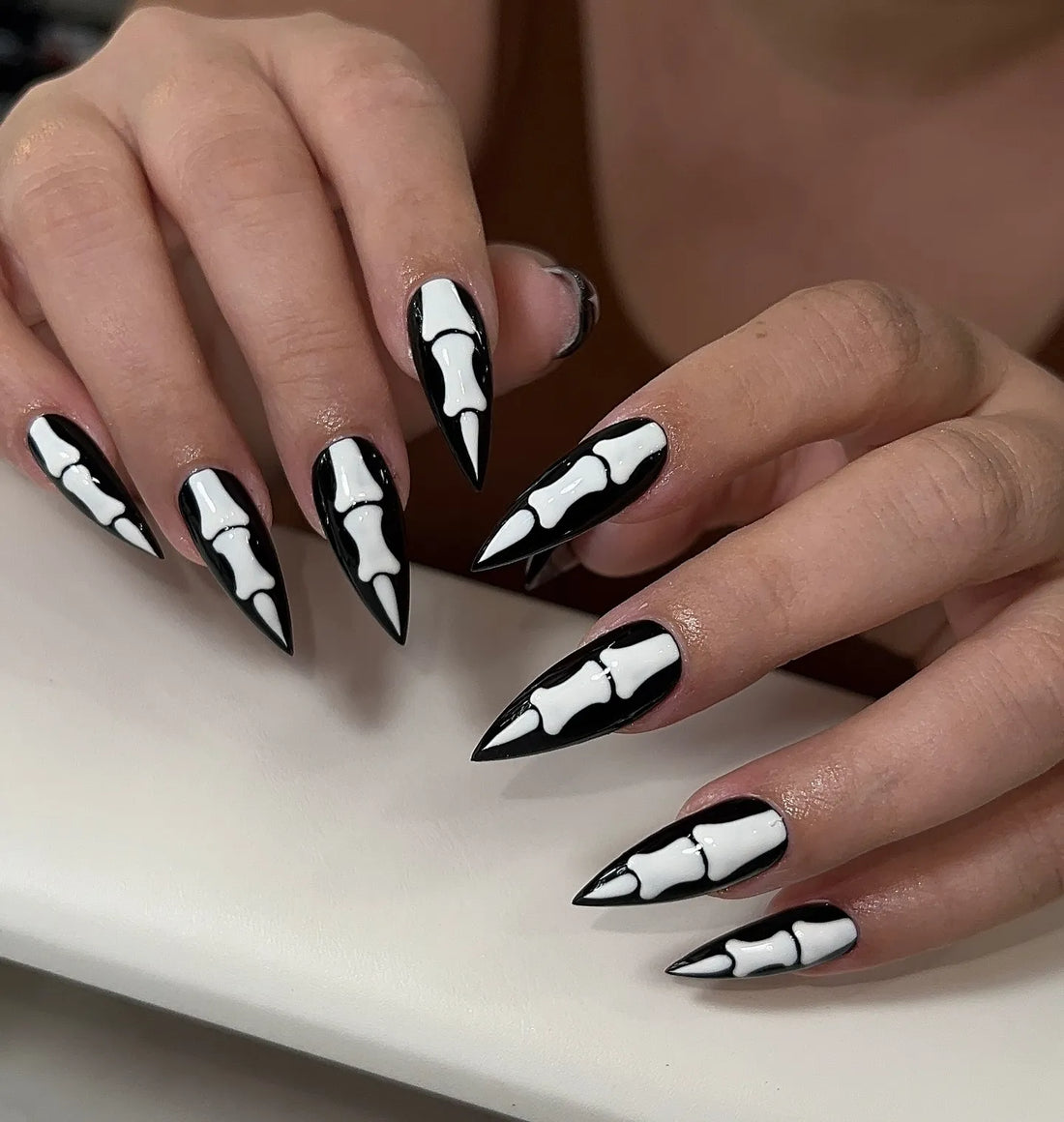 Handmade black stiletto press-on nails with white skeleton bone gothic Halloween design.