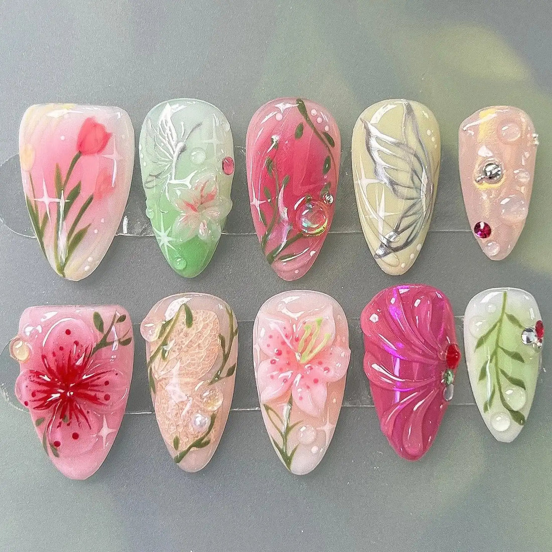 Handmade spring garden floral press-on nails with pink, green, and nature-inspired art designs.