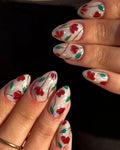 Handmade stained glass press-on nails with red floral and green leaf designs on a silver base