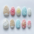 Handmade pastel beach press-on nails with starfish, seashell, and floral designs on white background.