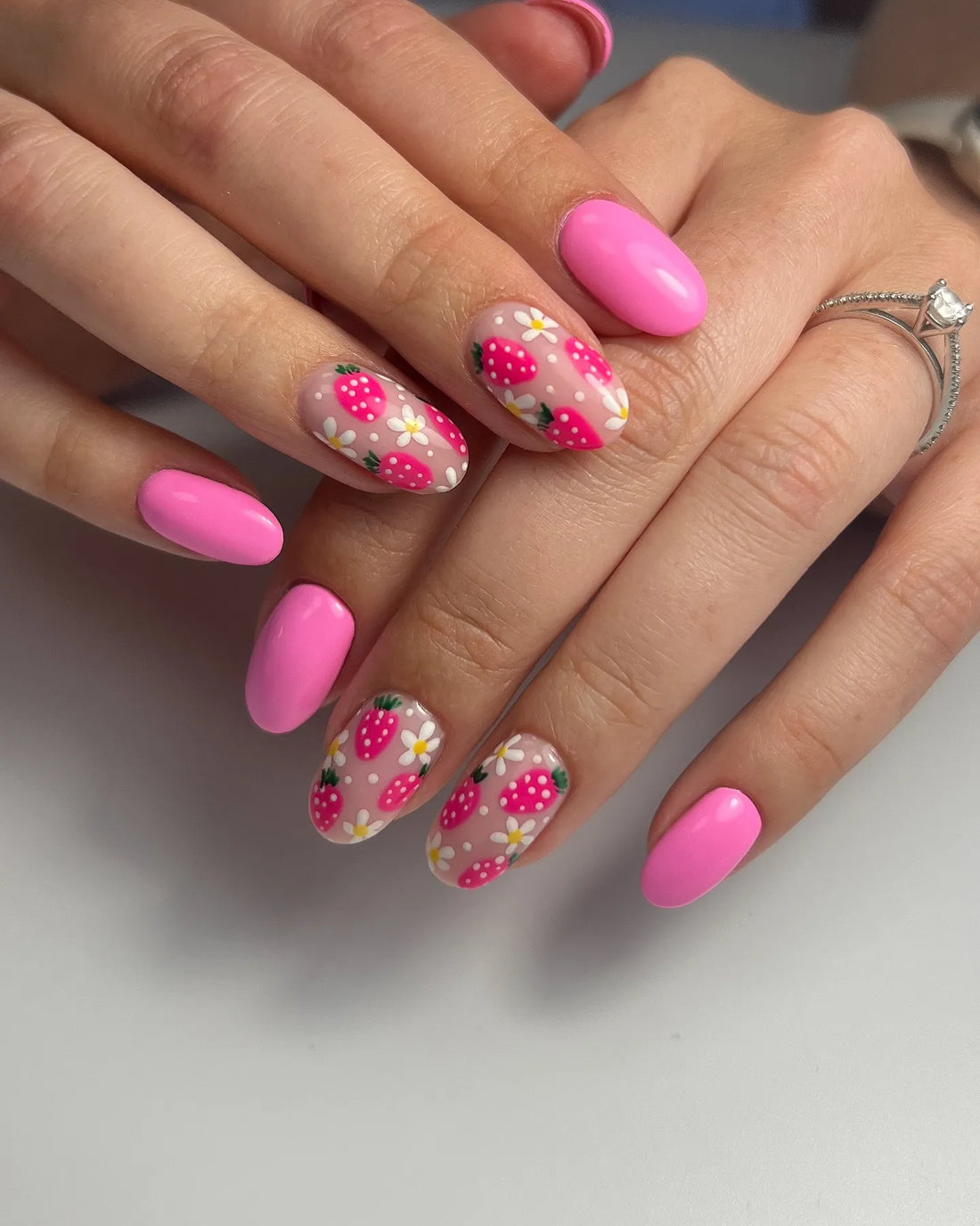 Handmade pink press-on nails with strawberry and daisy floral designs