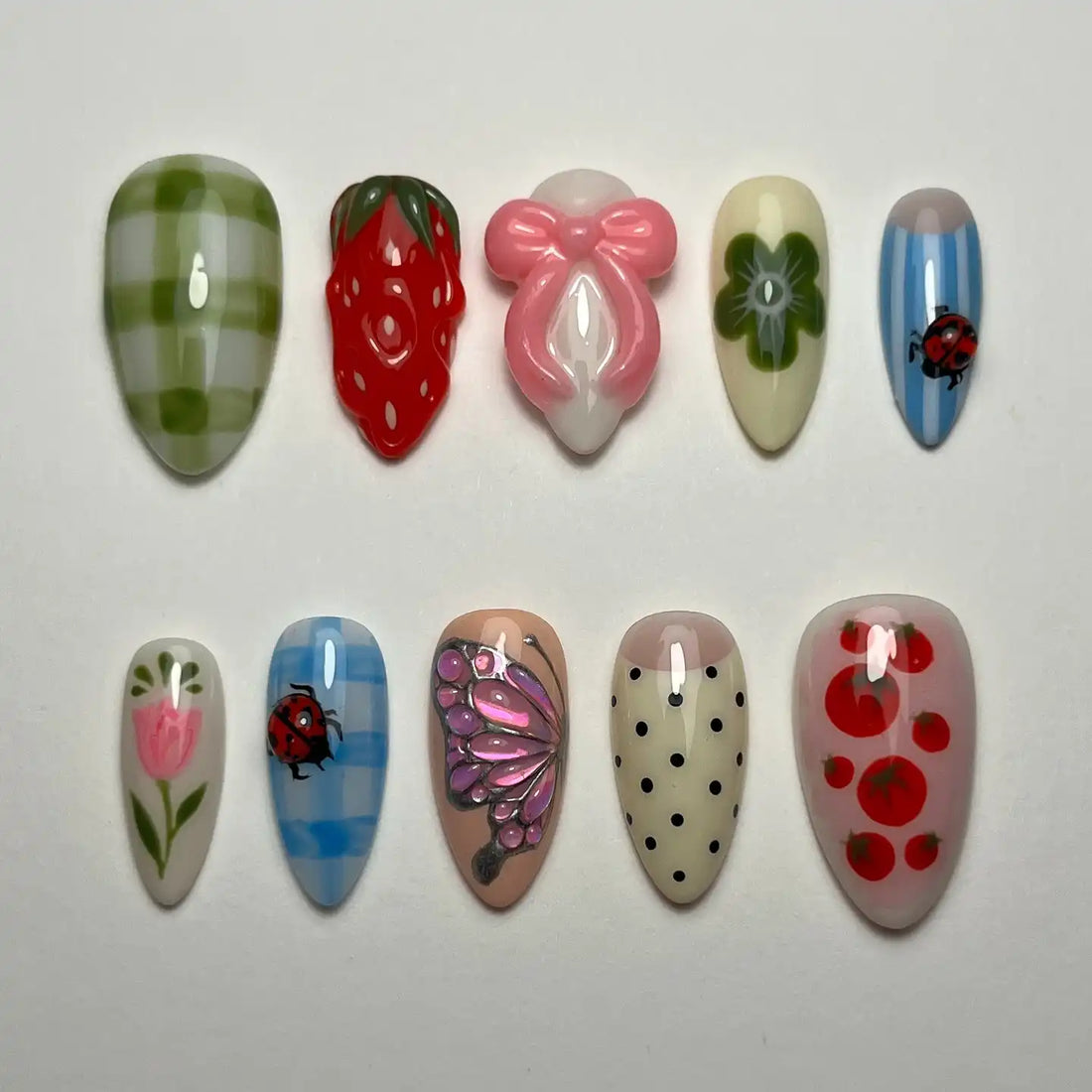 Handmade press-on nails with strawberry, gingham, ladybug, flower, polka dot, and butterfly designs.