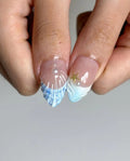 Hand holding blue and white mermaid French style 3D floral press-on nails with pearl and star accents