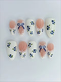 Handmade press-on nails with blue floral and gingham bow designs, lace ribbon accents
