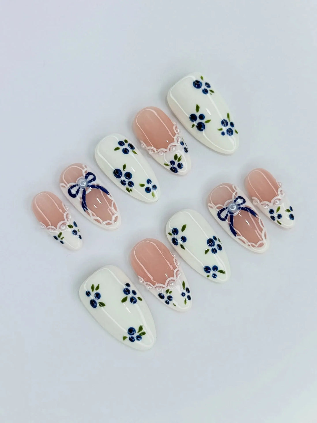 Handmade press-on nails with blue floral and gingham bow designs, lace ribbon accents