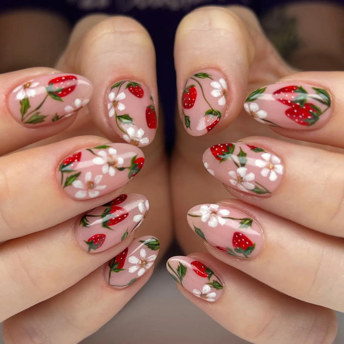Handmade press-on nails with pink base, strawberry and white floral summer nail art.