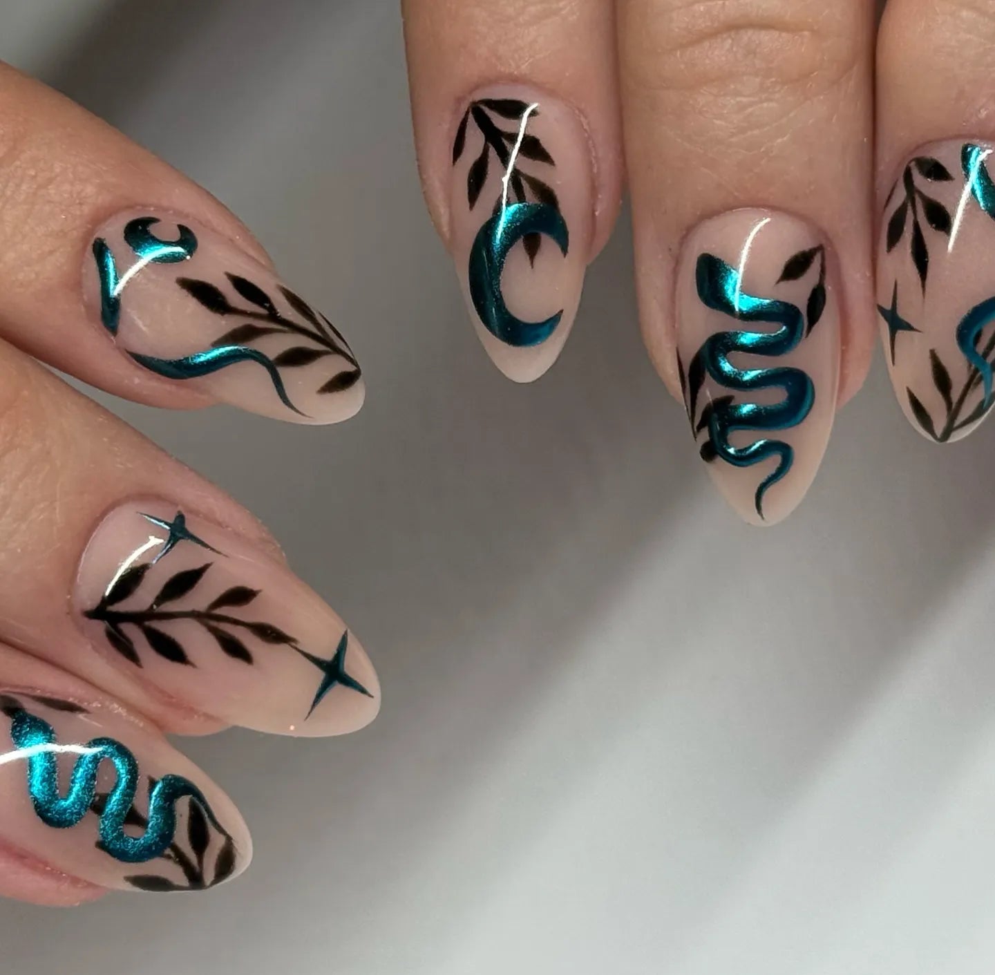Handmade press-on nails with teal chrome snake, moon, star, and leafy gothic celestial designs.
