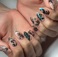 Handmade press-on nails with teal chrome snake, moon, stars, and black leafy designs