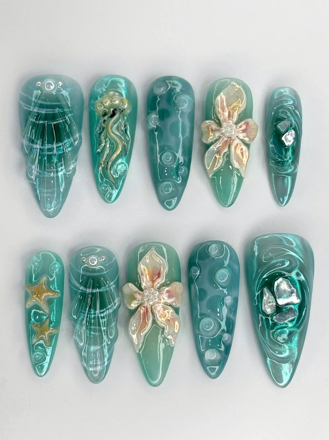 Handmade teal shimmer press-on nails with 3D ocean designs, jellyfish, starfish, and shells.