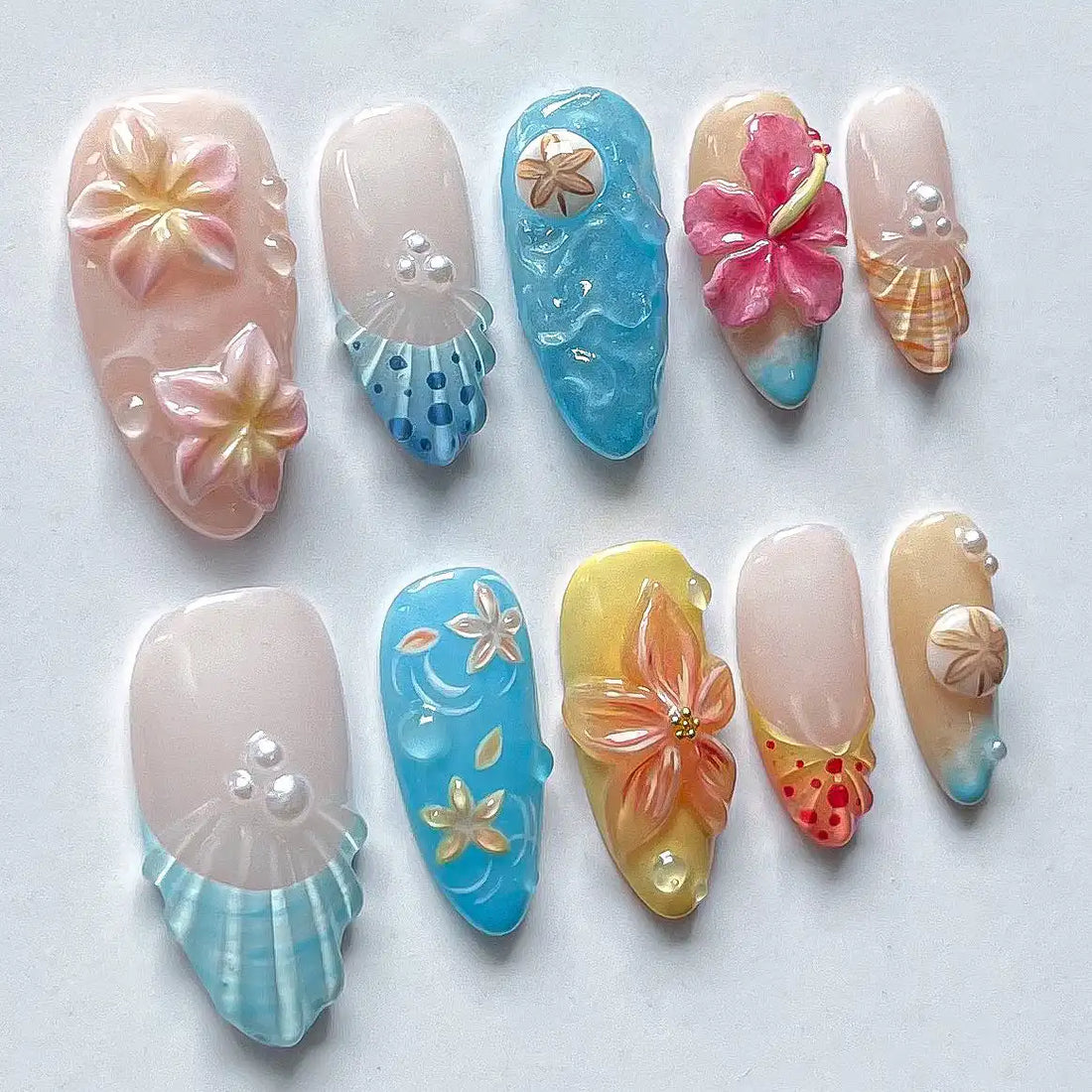 Handmade tropical flower and seashell press-on nails with beach vacation designs.