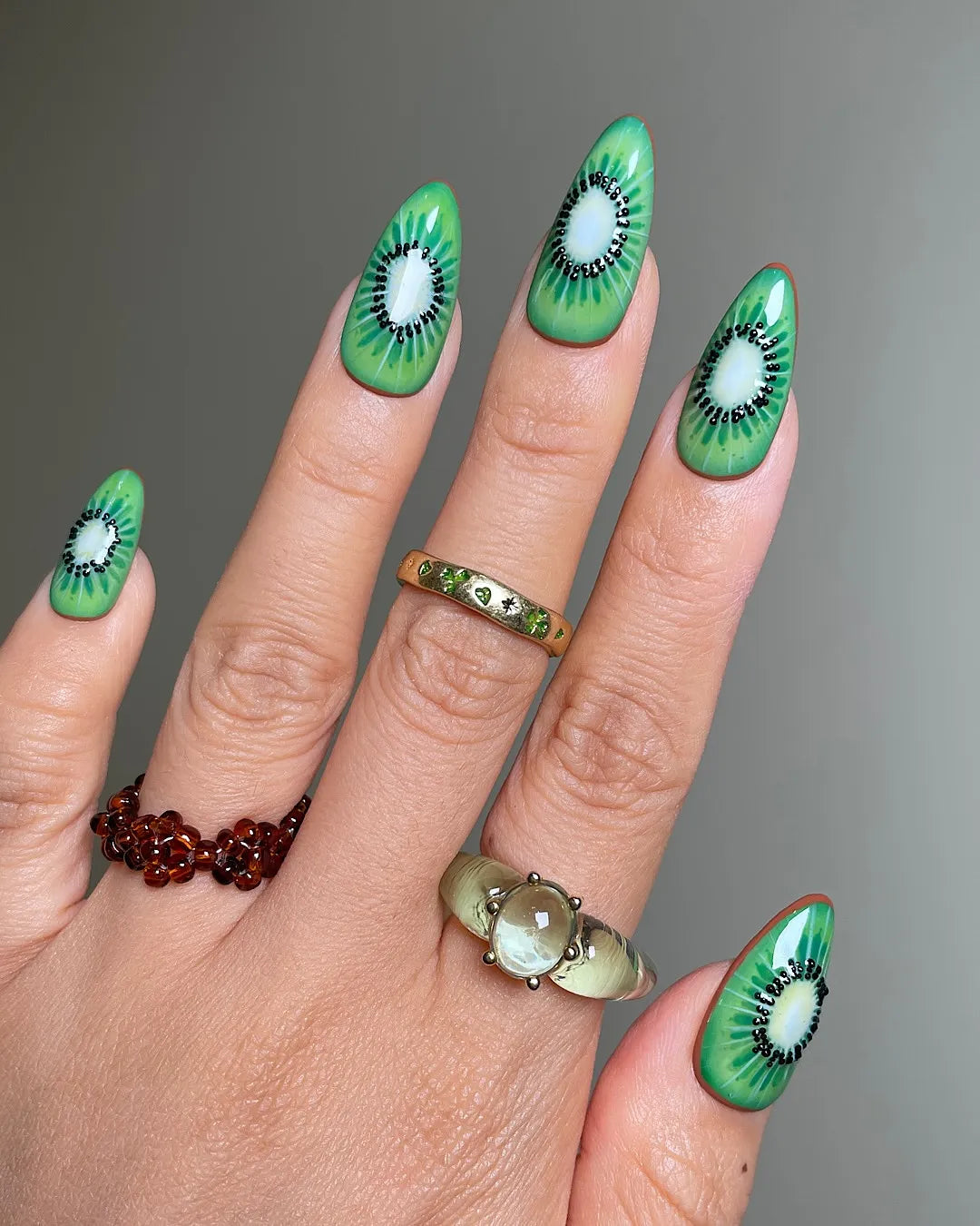 Hand with handmade tropical kiwi fruit press-on nails, green summer nail art design
