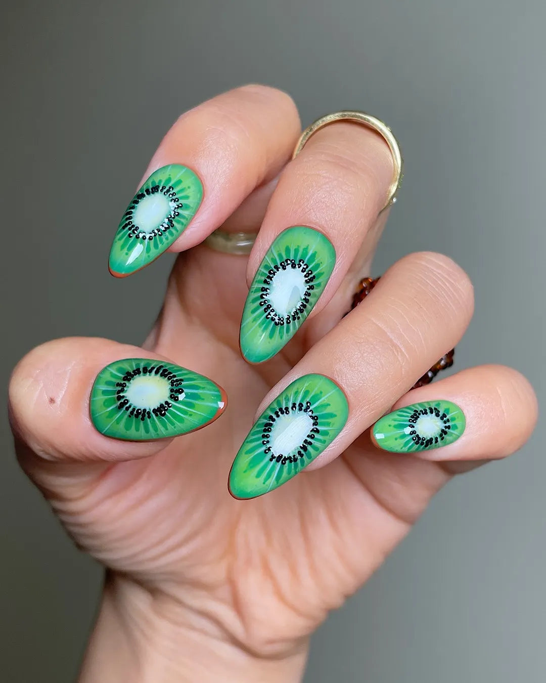 Hand with handmade tropical kiwi fruit press-on nails, green summer nail art design