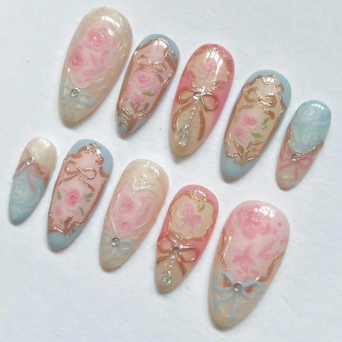 Handmade vintage press-on nails with pink and blue pastel floral and rose gold bow designs.