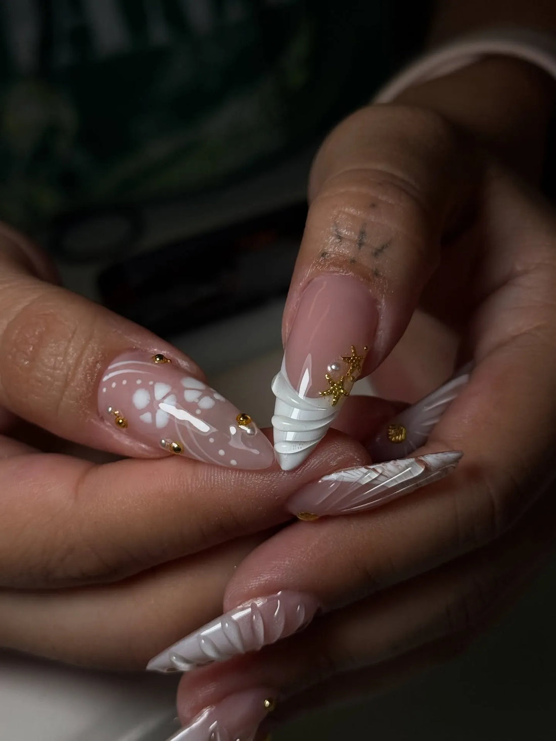 Handmade white 3D shell floral press-on nails with gold stud accents on natural hands
