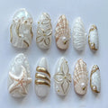 Handmade white and gold press-on nails with seashell, starfish, jellyfish, ocean designs.