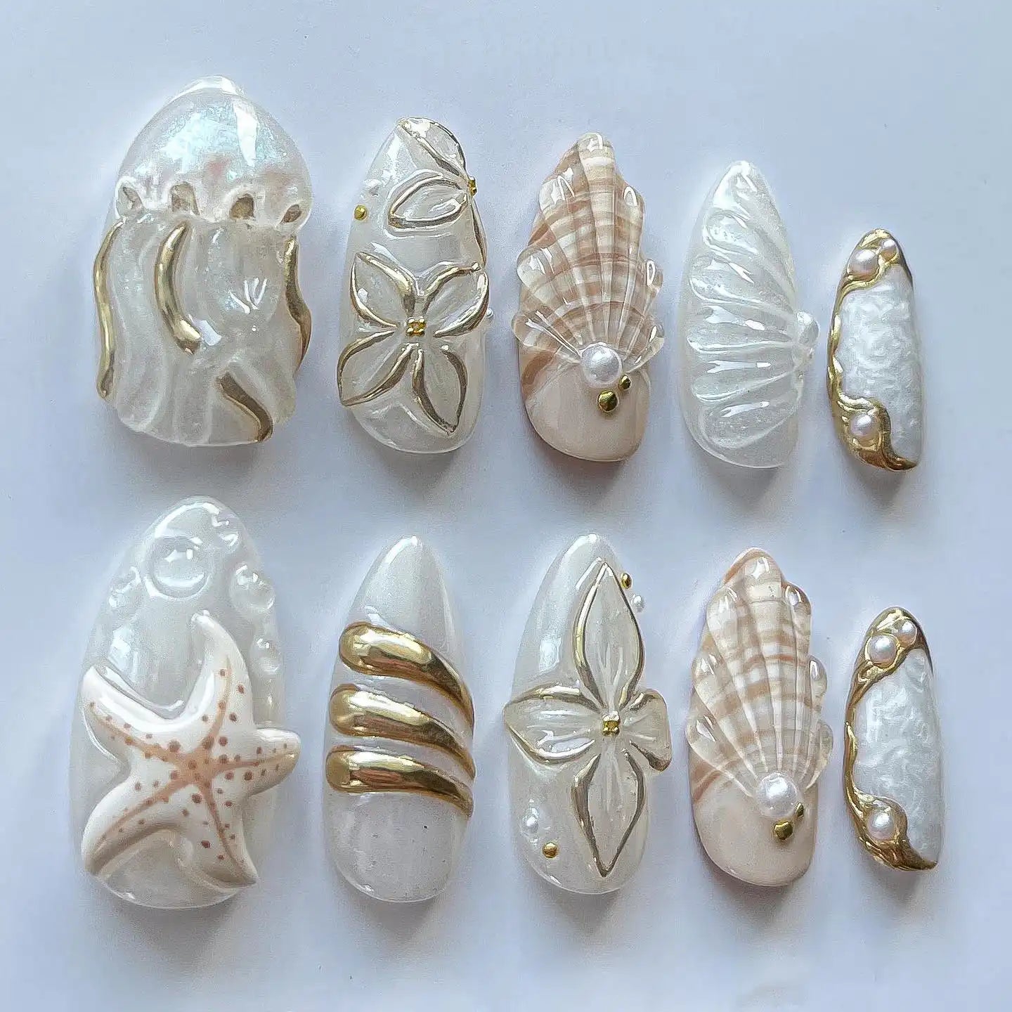 Handmade white and gold press-on nails with seashell, starfish, jellyfish, ocean designs.