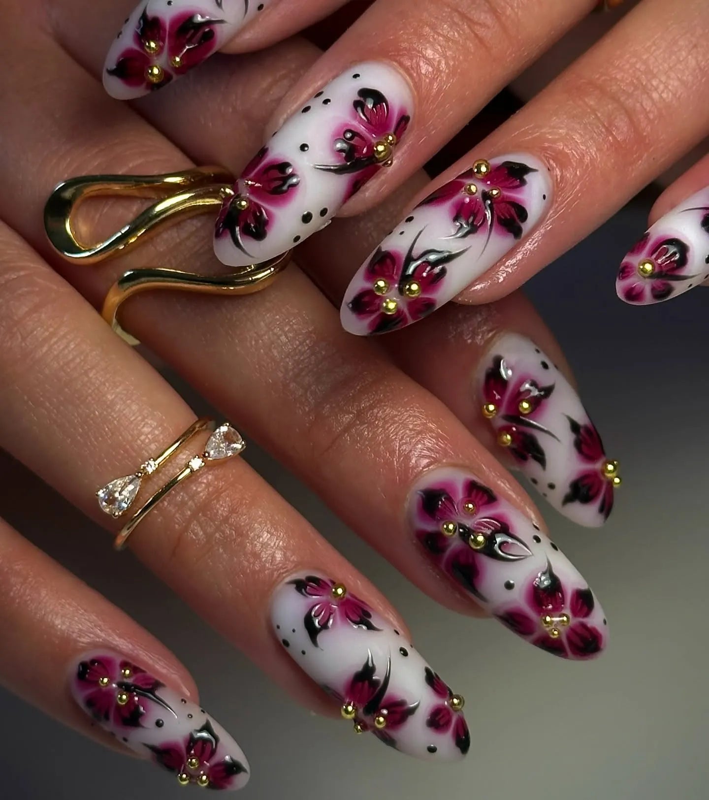 Handmade white and pink floral press-on nails with gold dotted accents, almond shape