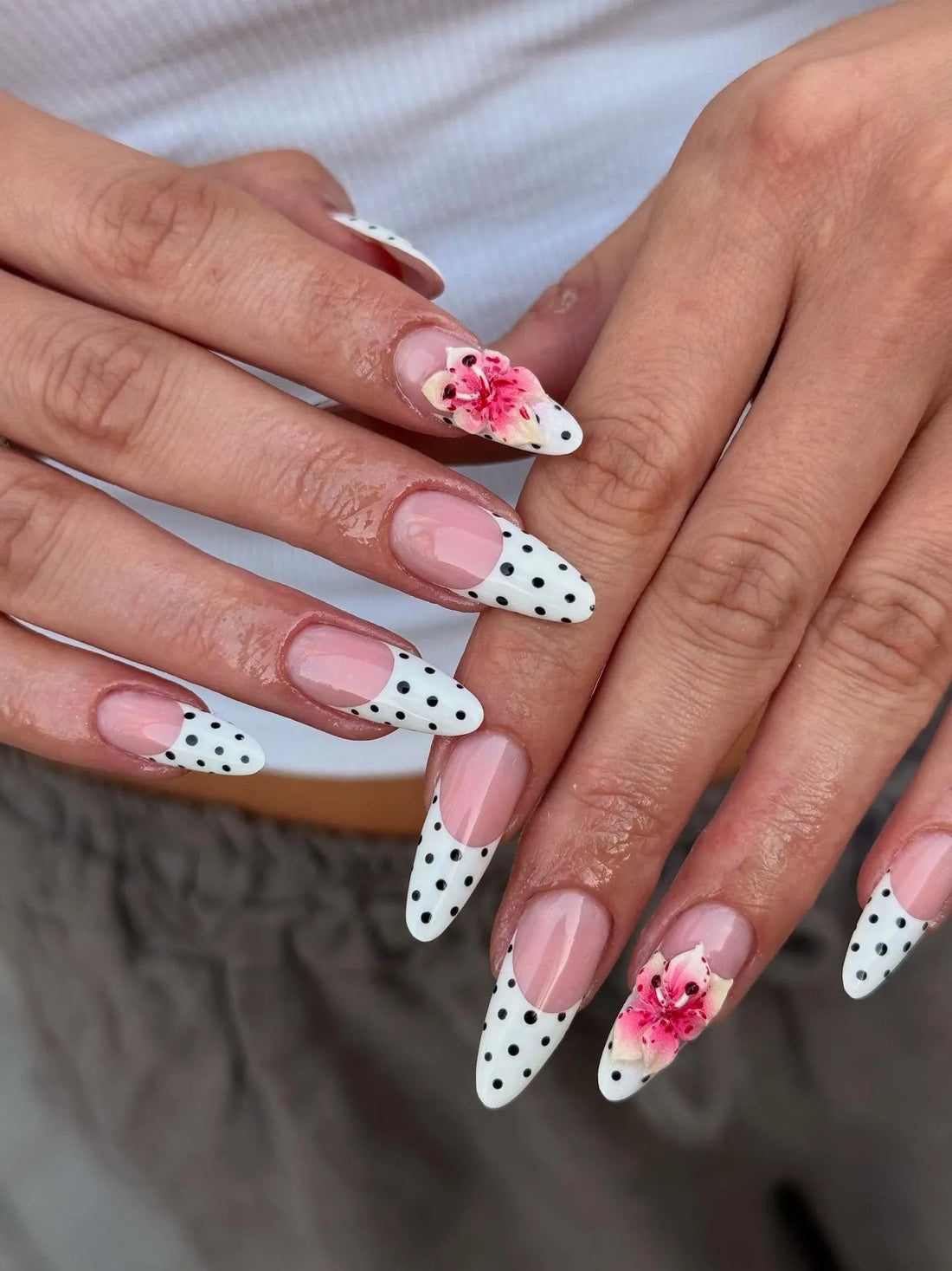 Handmade press-on nails with white polka dot French tips and pink floral accents.